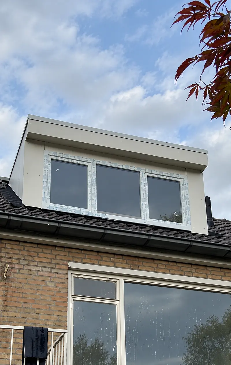 Nieuw geplaatste dakkapel met drie ramen en witte panelen op een pannendak.