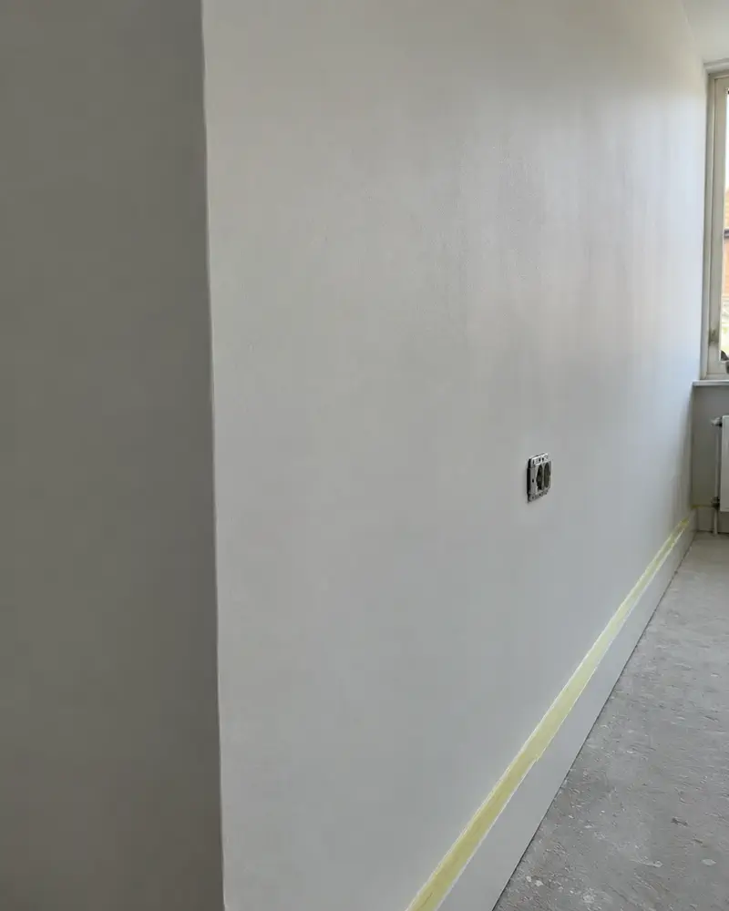 Sfeerbeeld: glad gestuukte binnenmuur met een strakke hoek en afplaktape langs de plint.